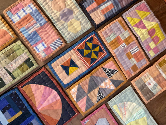 Multicolour patchwork purses placed in rows on a brown wooden background.