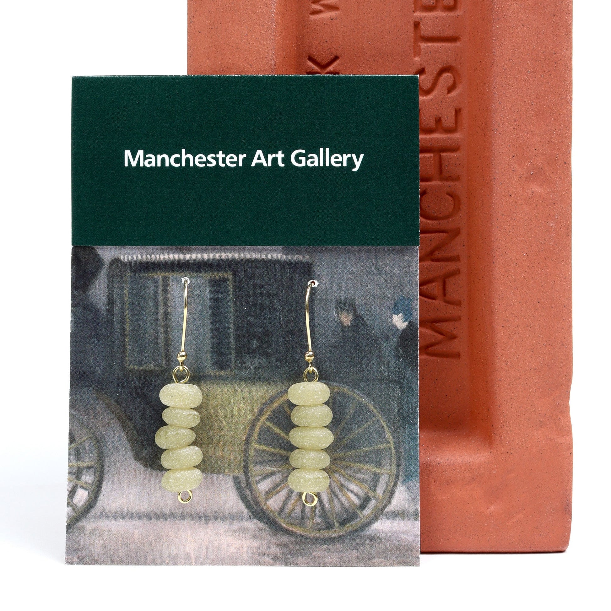 Earrings with beige beads displayed on a Manchester Art Gallery card