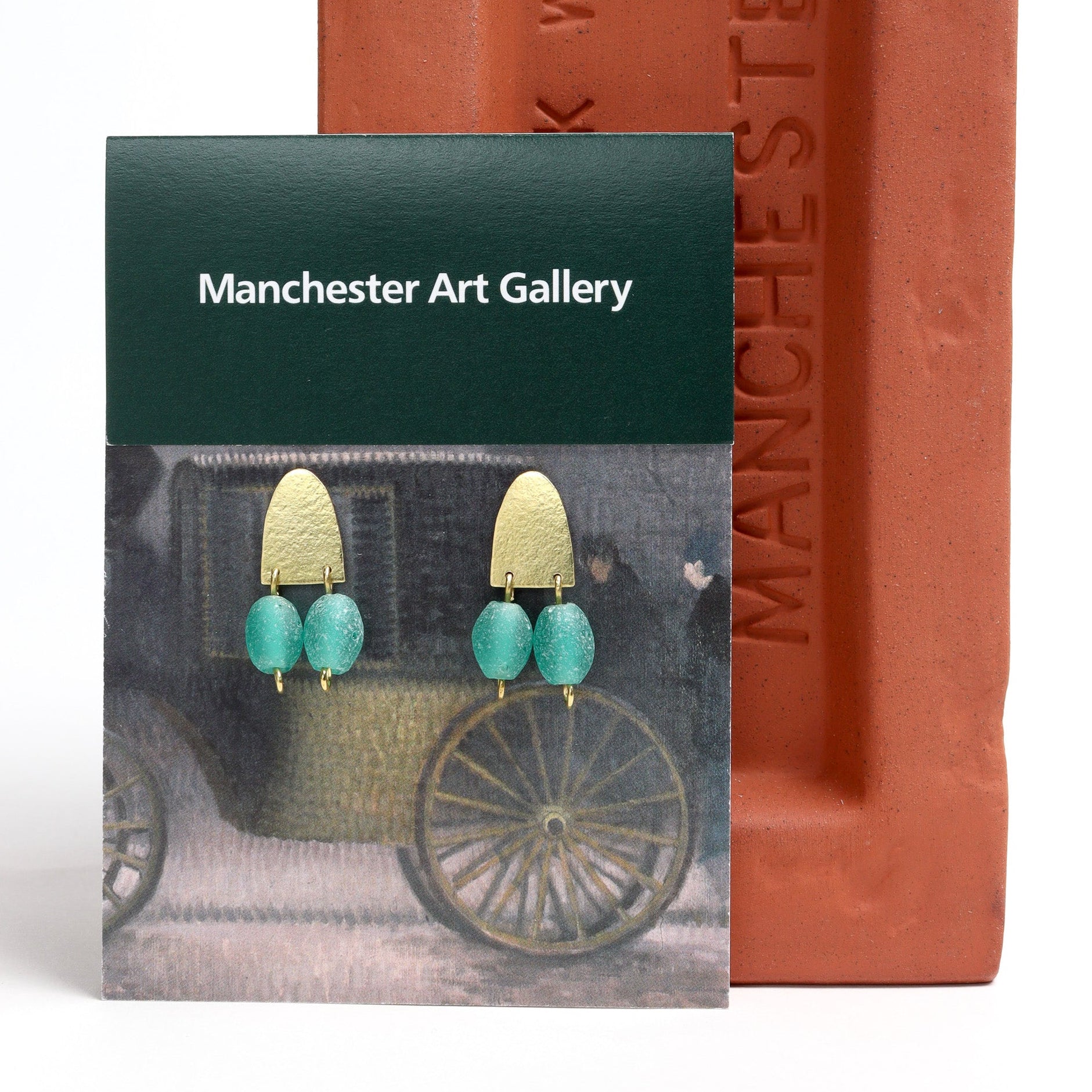 Earring packaging with 'Manchester Art Gallery' branding and earrings displayed.